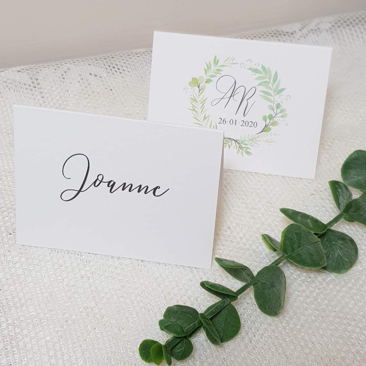 white place cards with a greenery wreath design