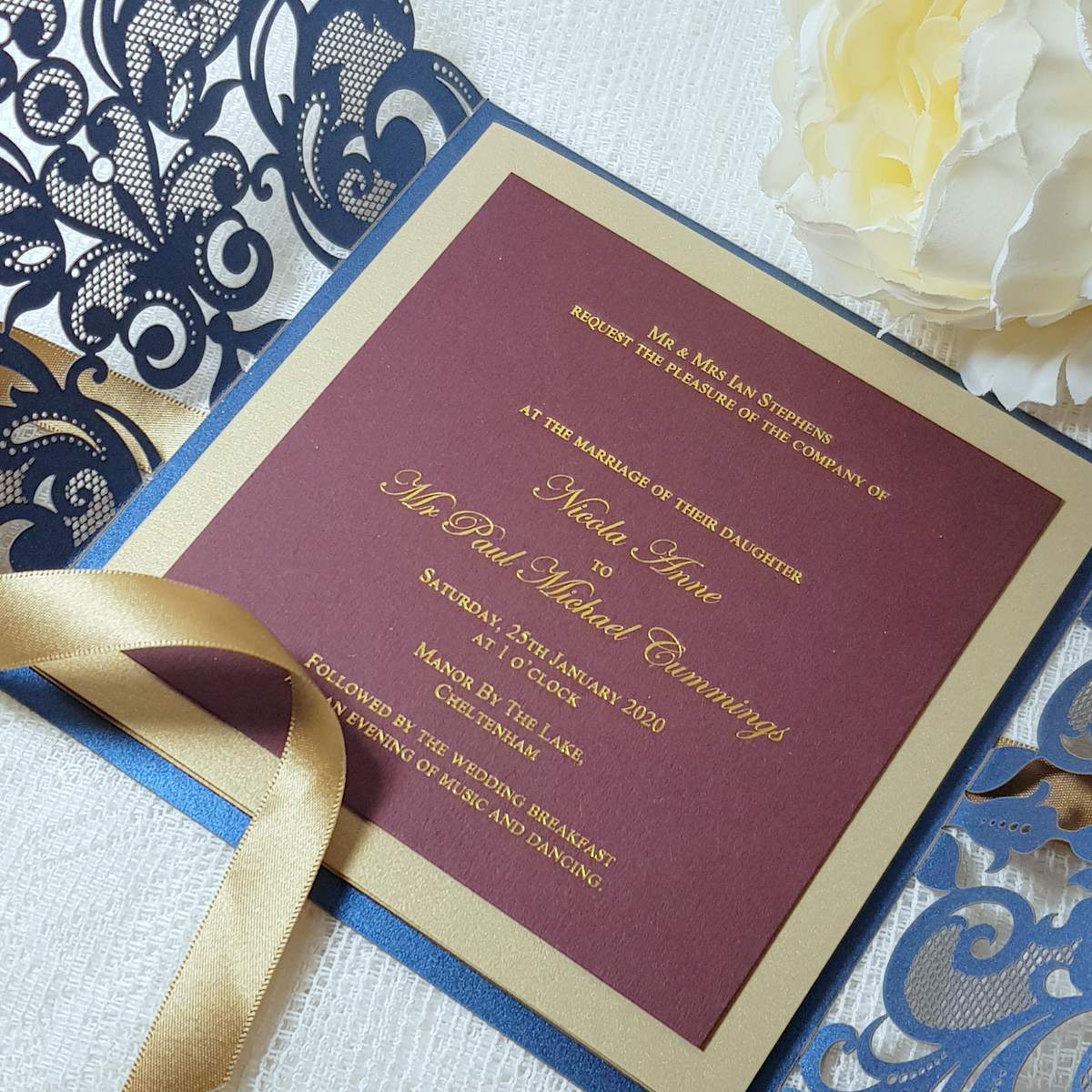 elegant burgundy and navy laser cut wedding invitation with gold foil print, and gold ribbon
