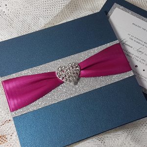 navy wedding invitation with silver glitter, magenta ribbon and diamante heart