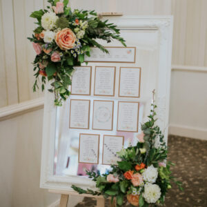 wedding table plan on a mirror with fresh floral accents to corners