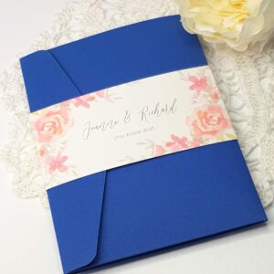blue pocketfold wedding invitation with a bellyband featuring coral roses
