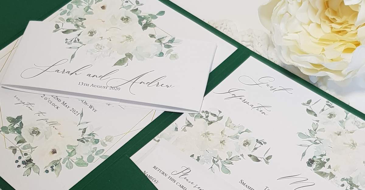 dark green pocketfold wedding invite with green and white flowers printed on the bellyband and inserts