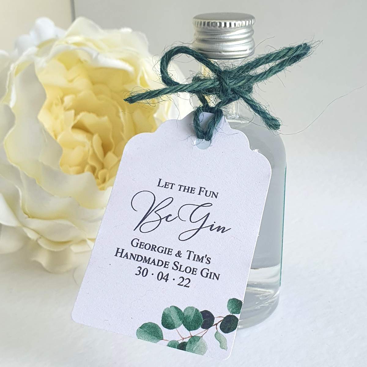a wedding favour miniature drink bottle with a tag saying let the fun begin
