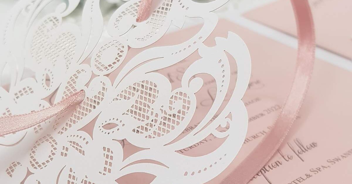 pretty blush pink wedding invitation with white lace laser cut detail