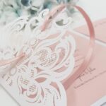 pretty blush pink wedding invitation with white lace laser cut detail