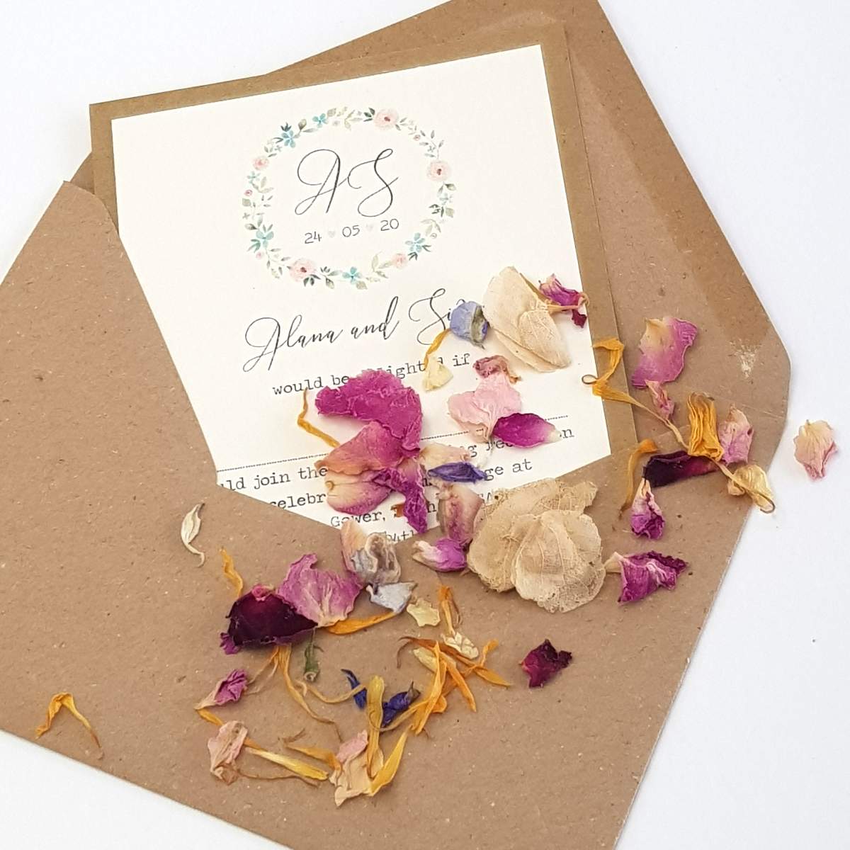 handmade rustic wedding invitation with flowers, a rustic recycled kraft envelope, sprinkled with colourful natural dried flower petal biodegradable confetti