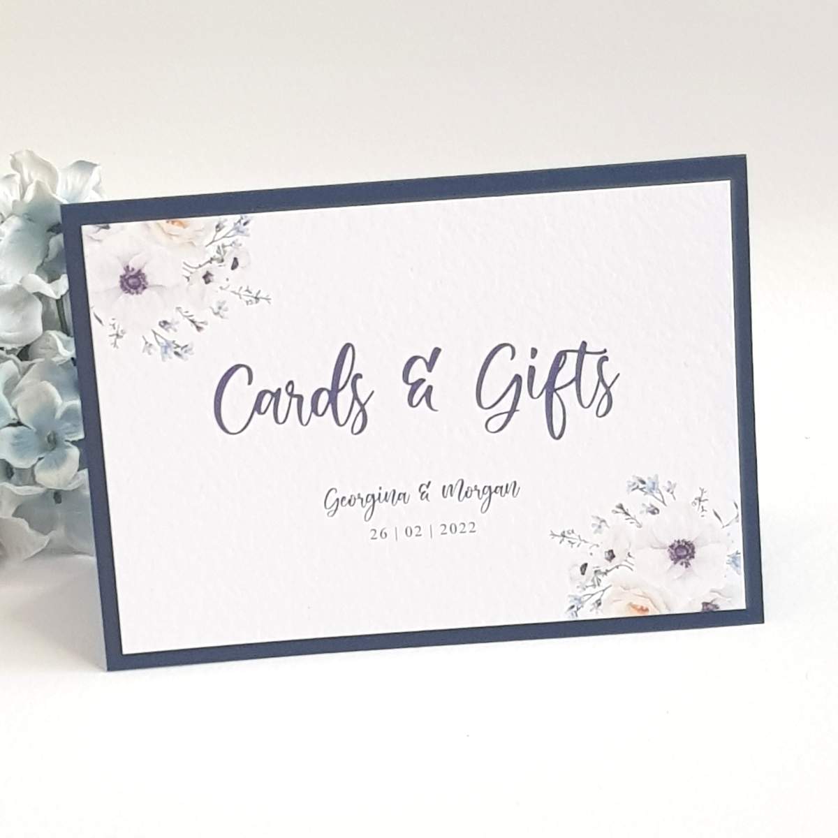A wedding sign for cards and gifts with navy text an anemone flowers