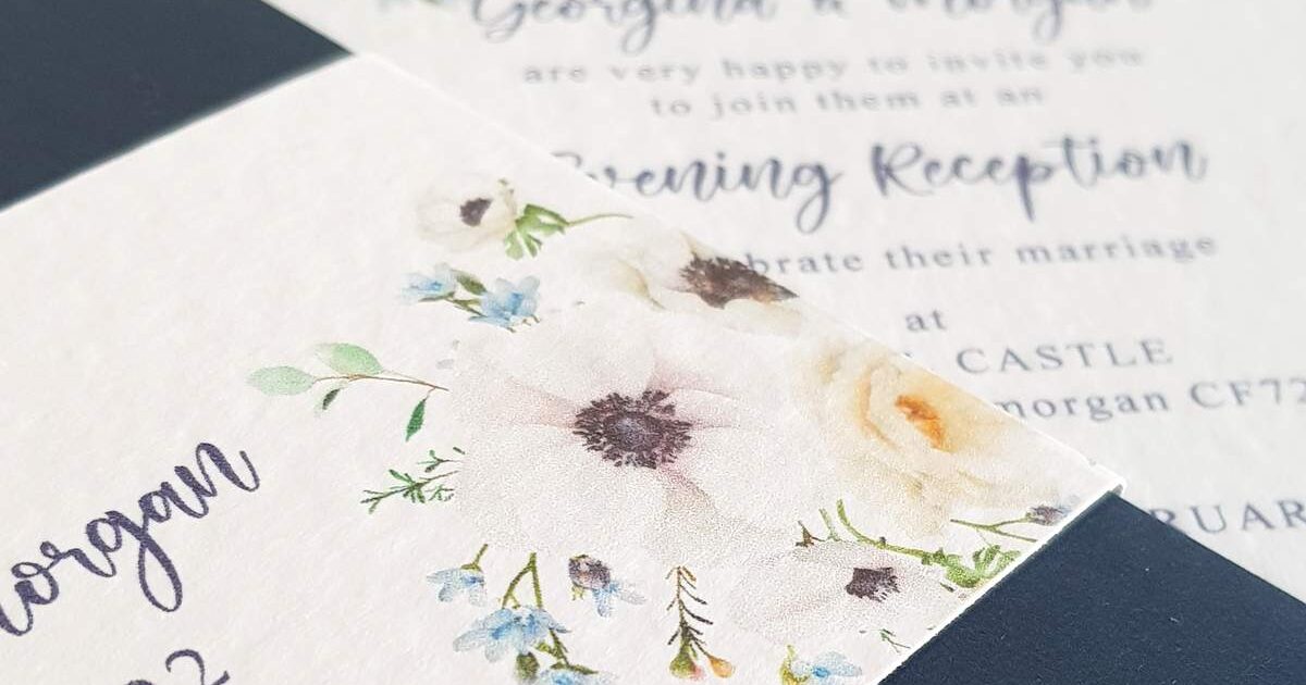 wedding invitations in a navy and white colour scheme with a floral anemone design
