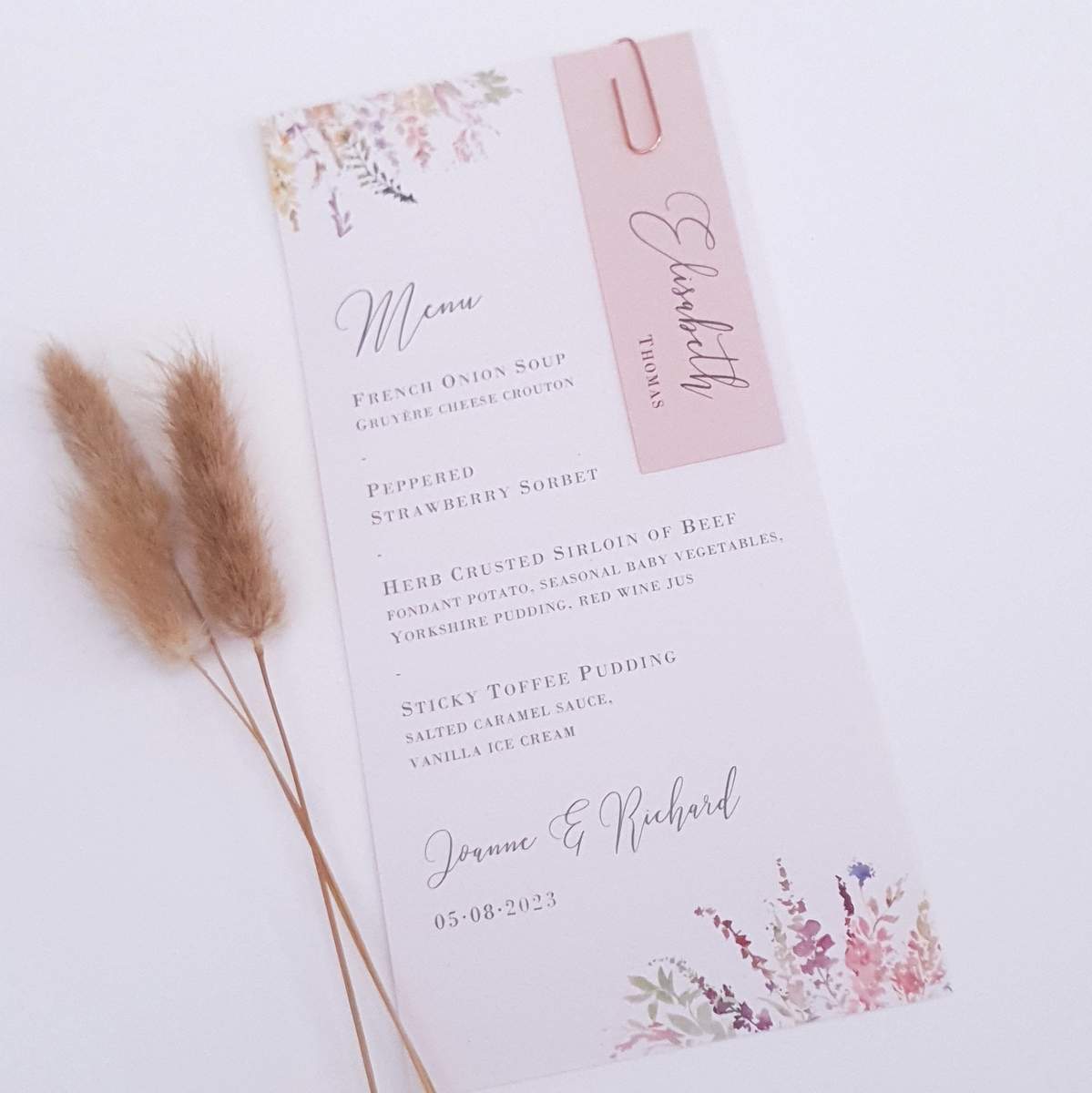 personalised wedding menu card with a pink name tag attached with a paperclip