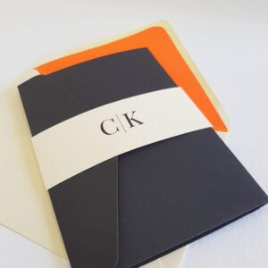 a black wedding invitation with a modern monogram design on the front, ivory and cream accents