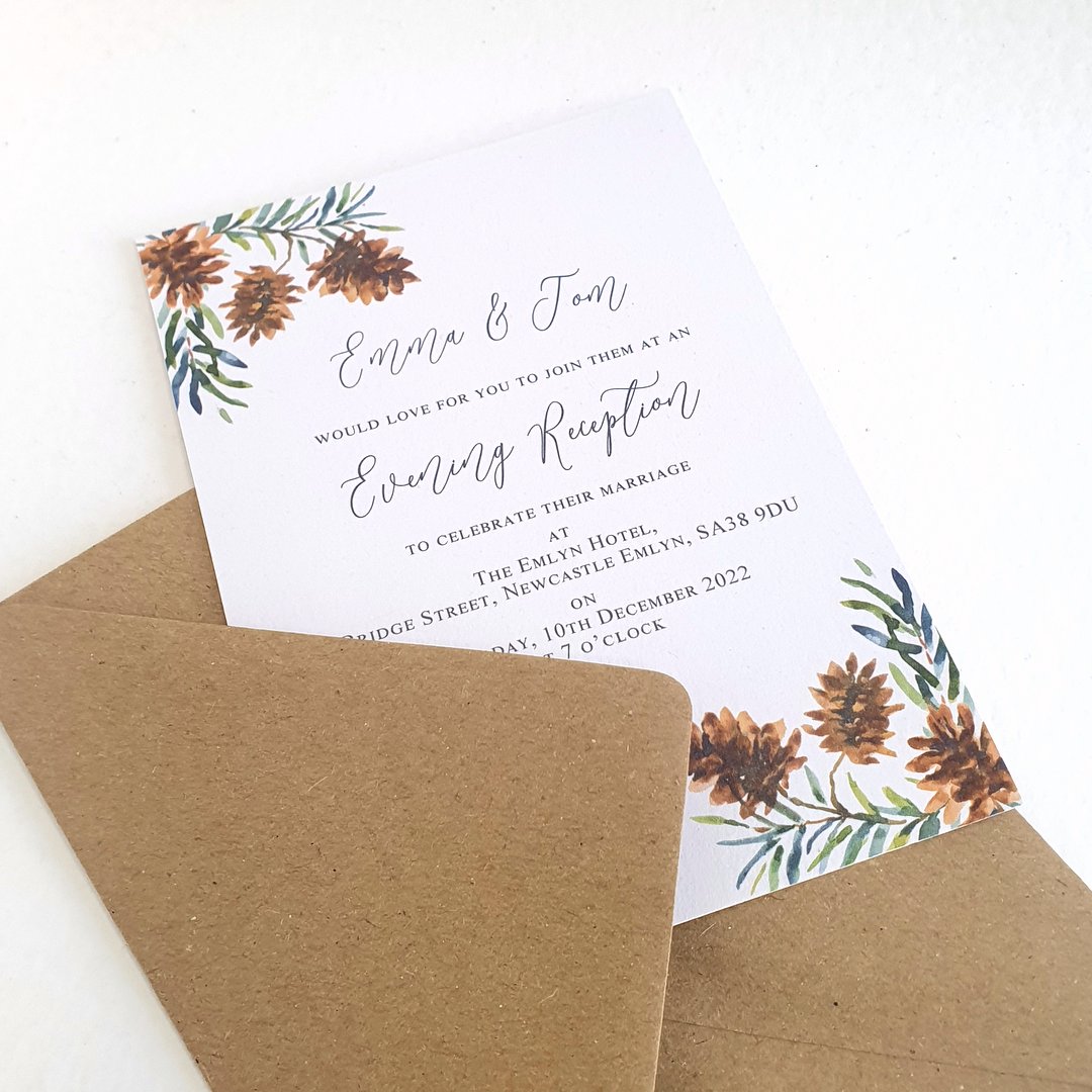 evening wedding invitations with a pine cone and evergreen design, shown with a recycled kraft brown envelope