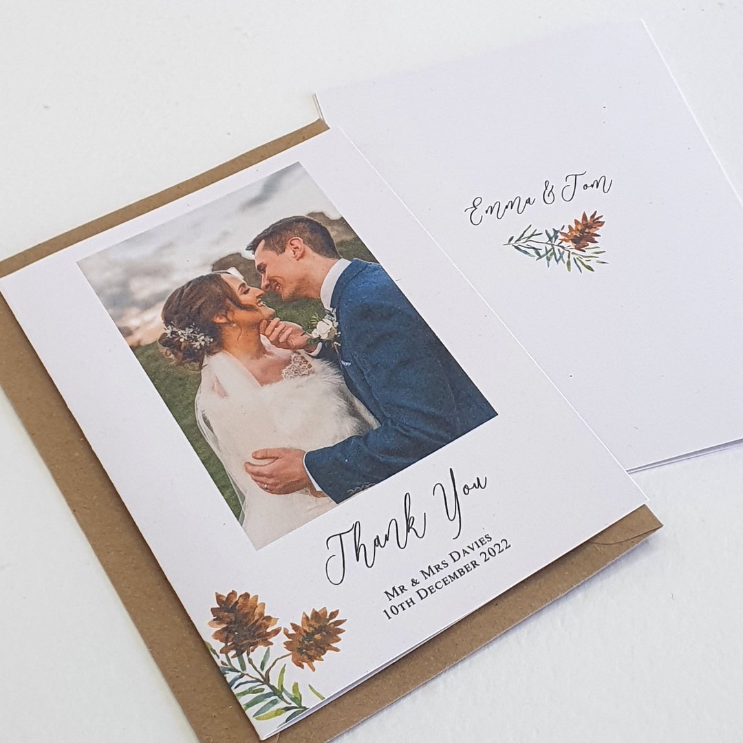 personalised wedding thank you cards, showing a picture of the happy couple and elemants of winter wedding evergreen and pine cones