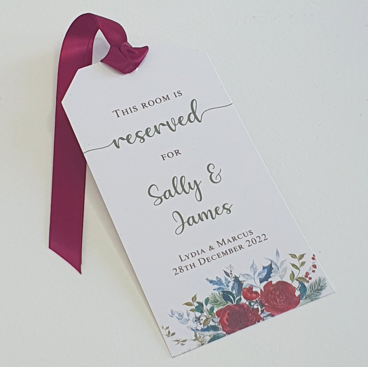 a tag with 'room reserved for sally and james, for a wedding guest room, decorated with a festive floral design in red and green