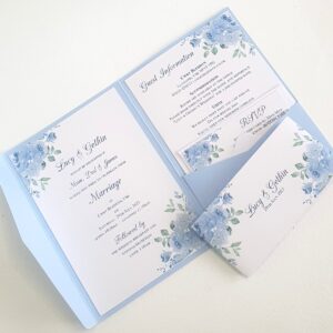 an open wedding invitation showing inserts printed with a sky blue floral design