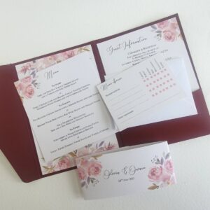 a wedding invitation with a burgundy card pocket and inserts printed with a mauve floral design
