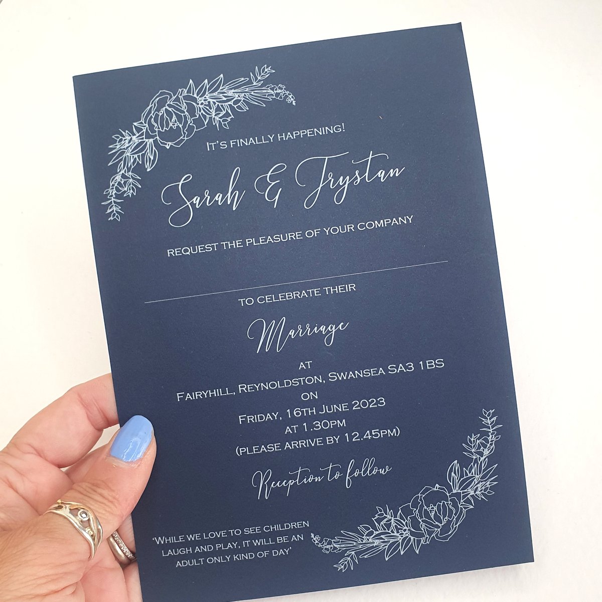 a white ink on navy blue bespoke wedding invitation with a floral design to the corners