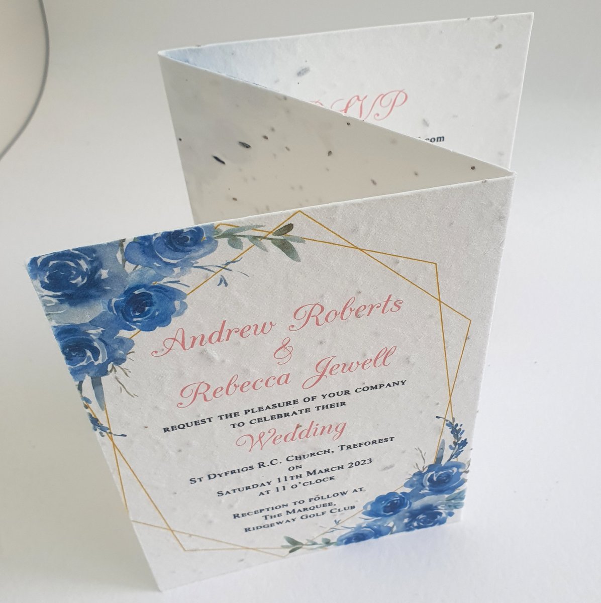 a wedding invitation with blue flowers and some pink decorative text, printed onto seed paper