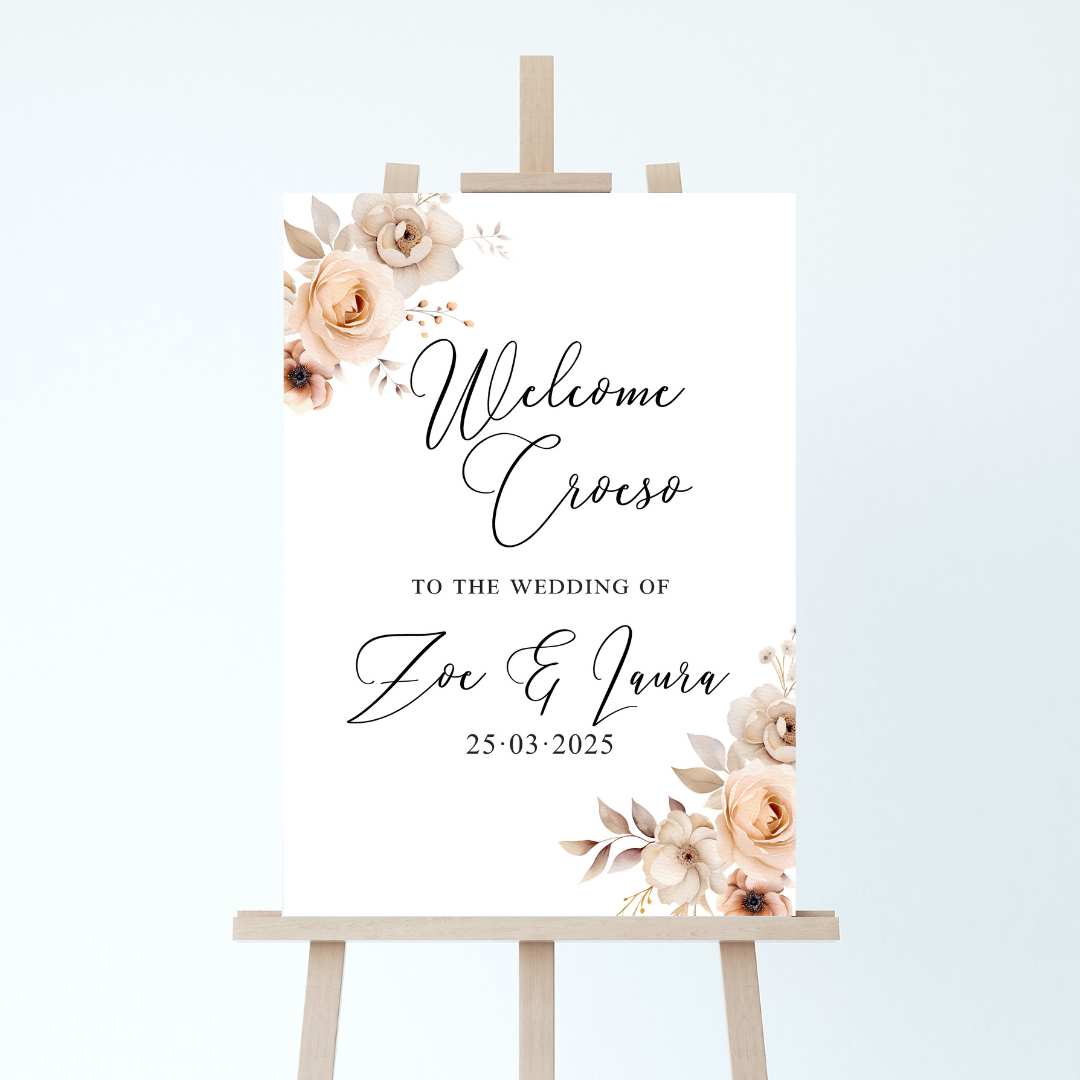 wedding welcome sign on an easel with champagne floral accents to the corners