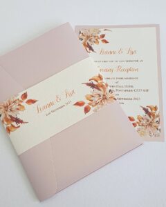 wedding invitation with a pink pocket folder and a belly band with an autumnal print