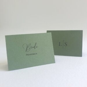 modern green wedding place cards with the guest name on the front and a monogram design on the back