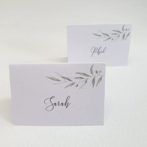 wedding place cards with the guest name printed in a script font and a simple olive branch design